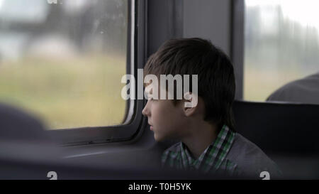 Ernsthafte junge ist das Reisen mit der Bahn schaut aus dem Fenster Stockfoto