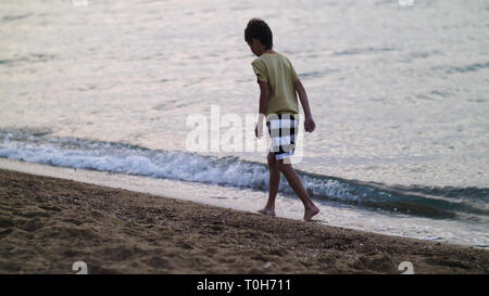 Junge ist zu Fuß entlang der goldenen Sand am Strand am Abend Stockfoto