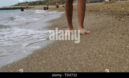 Junge ist zu Fuß entlang der goldenen Sand am Strand am Abend, Füße close-up Stockfoto