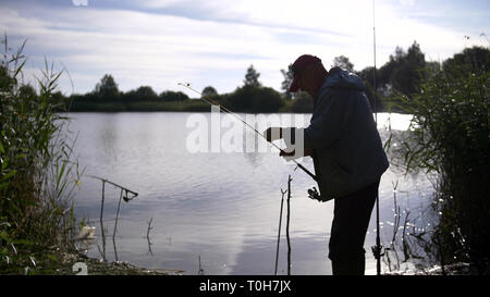 Silhouette Mann Angeln am Teich bei Sonnenuntergang Stockfoto