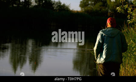 Mann Angeln am Teich bei Sonnenuntergang Stockfoto