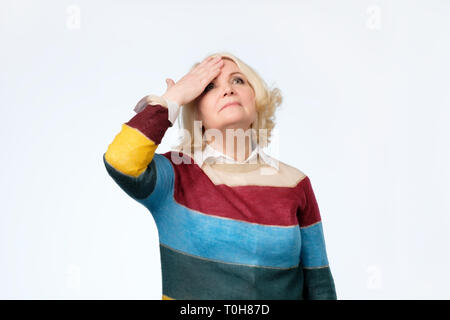 Ältere blonde Frau mit der Hand überrascht auf dem Kopf für Fehler, denken Sie daran, Fehler Stockfoto