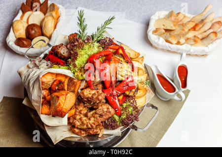 Mixed Grill Fleisch, gebratenes Gemüse und gegrillter Lachs Fischfilets Dekoration in warmen Gericht. Verschiedene köstliche gegrillte Kebab mit Kräutern auf Plat serviert. Stockfoto