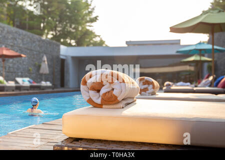 Handtuch auf die Liege mit Frau Schwimmer im Pool. Stockfoto