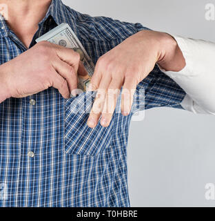 Mann in einem blauen Hemd setzt sich in einer Tasche einen Stapel Papier Geld, weißer Hintergrund Stockfoto