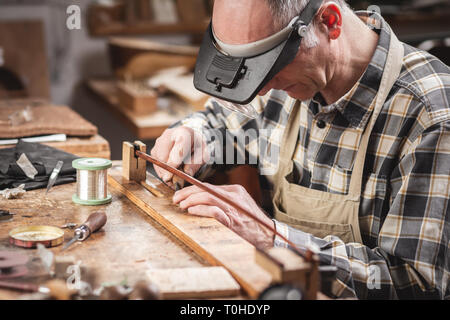 Geigenbauer in einem rustikalen Werkstatt arbeitet auf einem Bogen mit Präzision Stockfoto