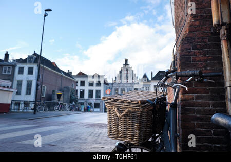 Altes Fahrrad mit Korb in der Dordrecht Stadt - typische Fassade und Gebäude mit Wasserstraßen - Niederlande - Holland. Stockfoto