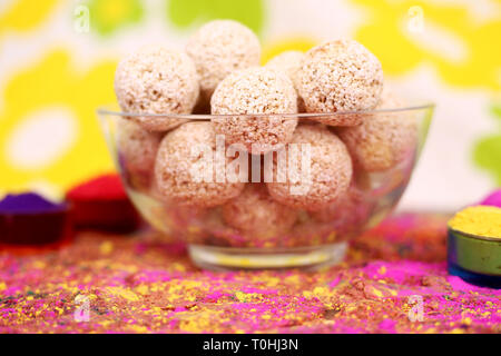 Bild von organischen Holi Farbe mit cholai ke ladoo in der Schüssel. Auf dem bunten Hintergrund isoliert. Stockfoto