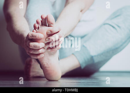 Causian Mann hält Hände an seine schmerzende Füße, Schmerzen im Fuß Stockfoto