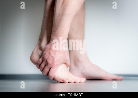 Causian Mann hält Hände an seine schmerzende Füße, Schmerzen im Fuß Stockfoto