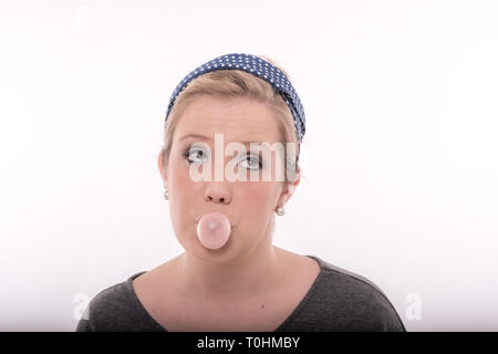 Hübsche, junge blonde Frau mit großen, leuchtenden Augen, trägt einen niedlichen retro Outfit, Blasen Pink Bubble Gum. Stockfoto