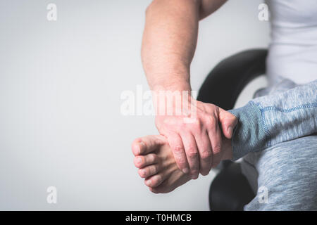 Causian Mann hält Hände an seine schmerzende Füße, Schmerzen im Fuß Stockfoto