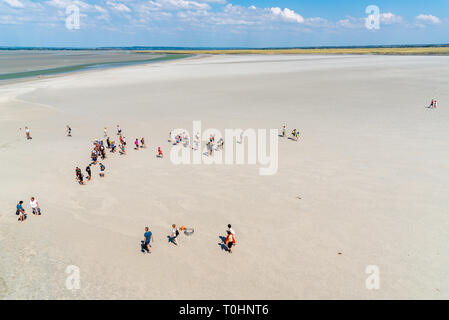 Mont Saint Michel, Frankreich - 25. Juli 2018: Die Gruppe der Wanderer in der Bucht bei Ebbe Stockfoto