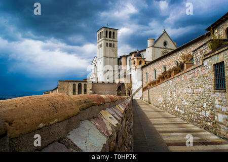 Landschaft der mittelalterlichen Stadt Assisi in Italien, mit den antiken und historischen Dorf und die Basilika von San Francesco mit dem Glockenturm unter einem Stockfoto