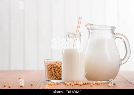 Kanne und Flasche Sojamilch und Tasse Bohnen. Hausgemachte nicht-Milchprodukte, alternative zu Kuhmilch. Stockfoto