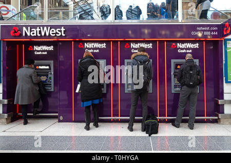 Menschen mit Geldautomaten in einer Reihe von Nat West Bank Geldautomaten im zentralen Eingangsbereich von der Liverpool Street Station, London Stockfoto