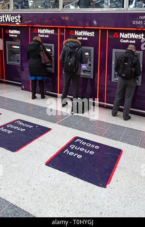 Menschen mit Geldautomaten in einer Reihe von Nat West Bank Geldautomaten im zentralen Eingangsbereich von der Liverpool Street Station, London Stockfoto