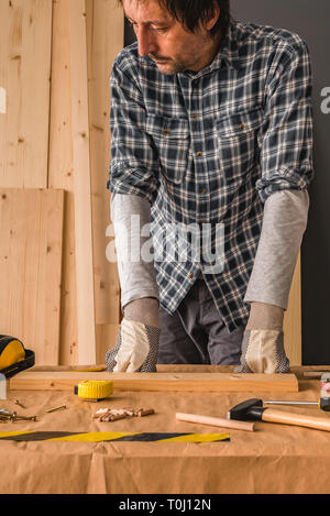 Carpenter plant Holzarbeitprojekt in Werkstatt, über dem Schreibtisch mit Brettern und Tools Stockfoto