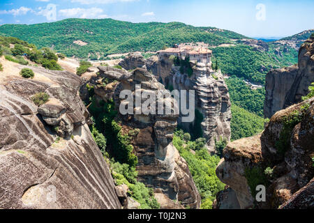 Blick von oben auf die Kloster Varlaam (der zweitgrößte) in Meteora, Griechenland, und der einzigartigen Felsformationen um ihn herum, oben Kalampáka Stadt, auf einem hellen s Stockfoto