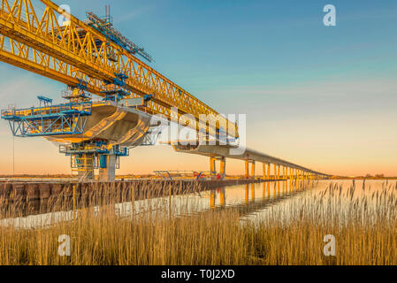 Baustelle von Kronprinzessin Mary Brücke über den Roskilde Firth in den Sonnenuntergang, eine riesige gelbe Kran im Wasser widerspiegelt. Frederikssund, D Stockfoto