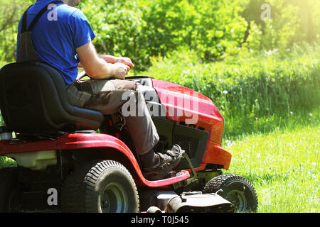 Gärtner fahren reiten rasenmäher in einem Garten. Stockfoto