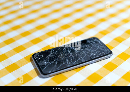 Konzept des smart phone mit defekten Bildschirm. Draufsicht auf gelben Hintergrund. Risse, zerschmettert, LCD-Touchscreen auf modernen Handys. Gadget muss repariert werden Stockfoto