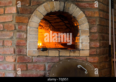 Brand im Steinofen. Backofen aus Stein und Lehm auf dem Holz. Ofen für Pizza. Gemauerter Ofen. Stockfoto
