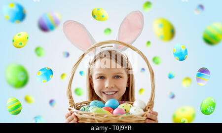 Glückliches Mädchen mit bunten Ostereier im Korb Stockfoto