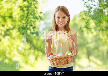 Glückliches Mädchen mit gefärbten Eiern in Weidenkorb Stockfoto