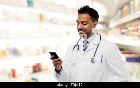 Lächelnd indischen männlicher Arzt mit Smartphone Stockfoto