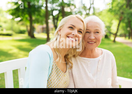 Tochter mit älteren Mutter sitzen auf einer Parkbank Stockfoto