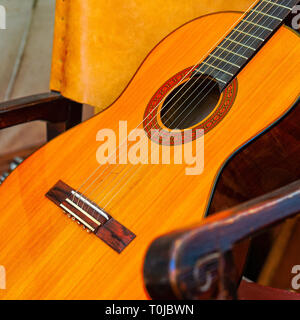 Klassische Gitarre Musical instruments legt in einem Sessel. Detailansicht. Platz Foto Stockfoto