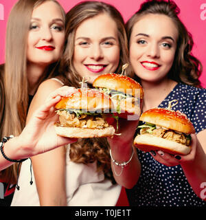 Hübsche Freundinnen mit saftigen Hamburger. Stockfoto