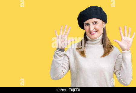 Reife Frau mittleren Alters tragen winter Pullover und Baskenmütze über isolierte Hintergrund angezeigt und zeigen mit den Fingern Nummer zehn, während lächelnd confid Stockfoto