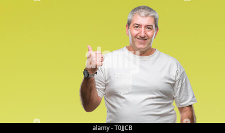 Gut aussehender älterer Mann über isolierte Hintergrund lächelnd mit glücklichen Gesicht und zeigt auf die Seite mit dem Daumen nach oben. Stockfoto