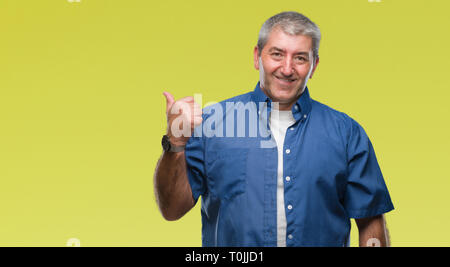 Gut aussehender älterer Mann über isolierte Hintergrund lächelnd mit glücklichen Gesicht und zeigt auf die Seite mit dem Daumen nach oben. Stockfoto