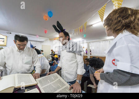 Elkana, Israel. 20 Mär, 2019. Lesung des Blättern von Esther, eine Synagoge während der jüdische Feiertag Purim. In diesem Urlaub Juden traditionell verkleiden sich, lesen Sie das Buch von Esther, eine Geschichte über ein anti-jüdischen fehlgeschlagen Grundstück im alten Persien, und, wann immer ein Schläger der Name Haman, der main Antagonist, erwähnt wird. Credit: Yagil Henkin/Alamy leben Nachrichten Stockfoto