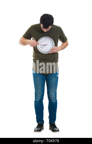 In voller Länge Porträt der jungen casual Mann hält eine Uhr in der Nähe der Körper auf weißem Hintergrund. Zeit-management und Planung Konzept. Zeitplan Stockfoto