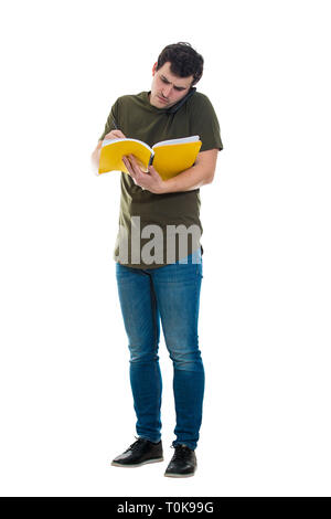 Volle Länge des geschäftigen Casual junger Mann zwei Dinge gleichzeitig tun, sprechen mit Telefon und Notizen in seinem COPYBOOK. Betroffenen Kerl holding Telefon mit einer s Stockfoto