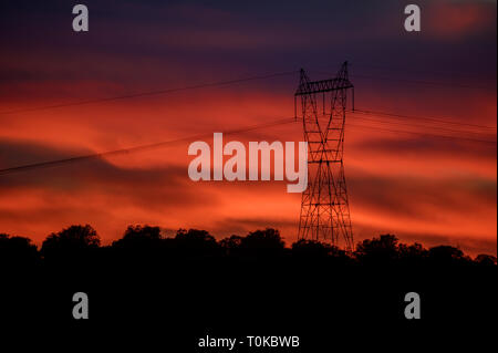 Hohe Spannung Strom Turm im Sonnenuntergang inder Landschaft Stockfoto