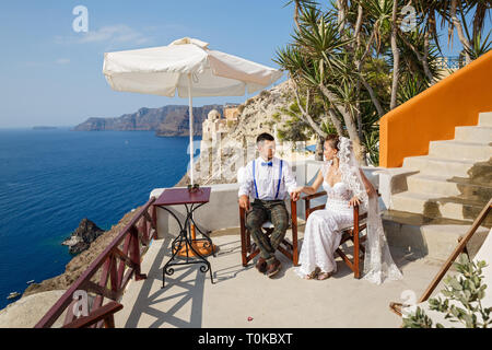 Die Braut und der Bräutigam am Tisch gegen das Meer sitzen, Insel Santorini Stockfoto