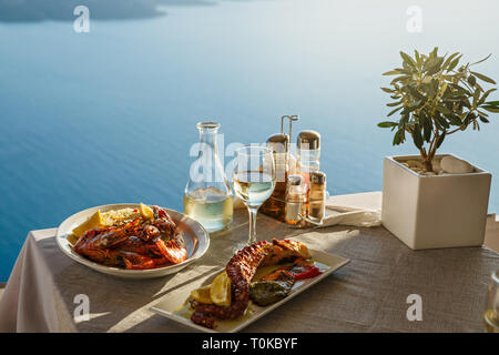 Romantisches Dinner zu zweit bei Sonnenuntergang. Griechenland, Santorini, Restaurant am Strand, über dem Vulkan. Stockfoto