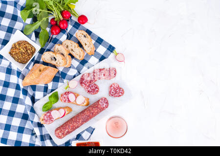 Vorspeisen Tabelle mit italienischen Antipasti, Snacks und Wein in Gläsern. Salami und Bruschetta mit frischem Gemüse auf einem weißen Hintergrund. Freier Speicherplatz für Stockfoto