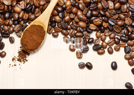 Geröstete Kaffeebohnen und gemahlener Kaffee in hölzernen Löffel auf Licht Tabelle, Ansicht von oben mit der Kopie. Stockfoto