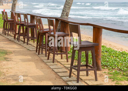 Hölzerne Stühle und Tisch in leeren Café neben dem Meerwasser am tropischen Strand, Sri Lanka. Nahaufnahme Stockfoto