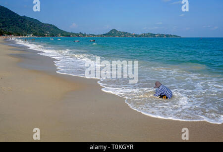Thai Frau Graben für Muscheln am Strand Lamai Beach, Koh Samui, Golf von Thailand, Thailand Stockfoto