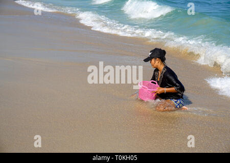 Thai Frau Graben für Muscheln am Strand Lamai Beach, Koh Samui, Golf von Thailand, Thailand Stockfoto