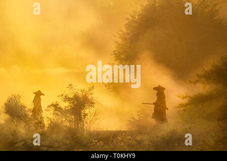 Zwei Männer sind auf einer staubigen Straße in Bagan, Myanmar Silhouette Stockfoto