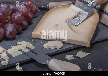 Gelb, klaren leckeren Käse aus Niederlande serviert mit Trauben auf einem Stein Platter. Stockfoto