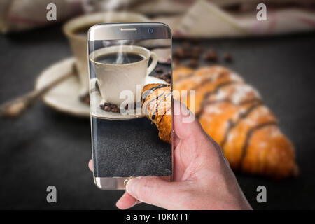 Mann, Foto der traditionellen französischen Frühstück Croissant mit Schokolade und Kaffee auf schwarzen Stein Tabelle Stockfoto
